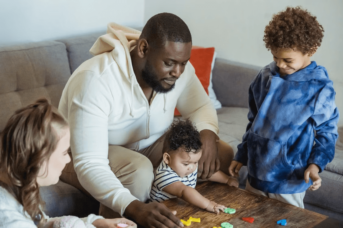 A parent sitting with their children at home, in the middle of an ordinary afternoon.